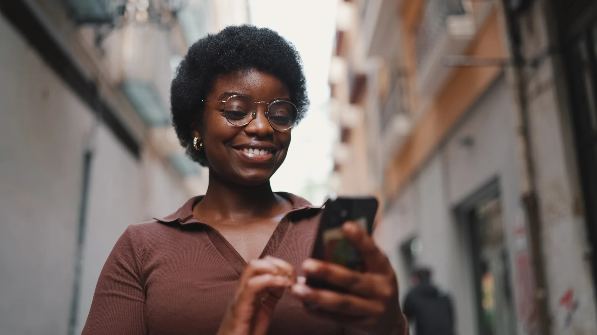 A smiling Nigerian woman sending money on her phone